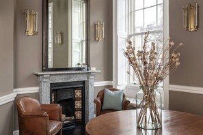 A room with a fireplace, leather armchairs, a round table, and a vase with dried flowers. - Former Prime Minister s Home (Bath)