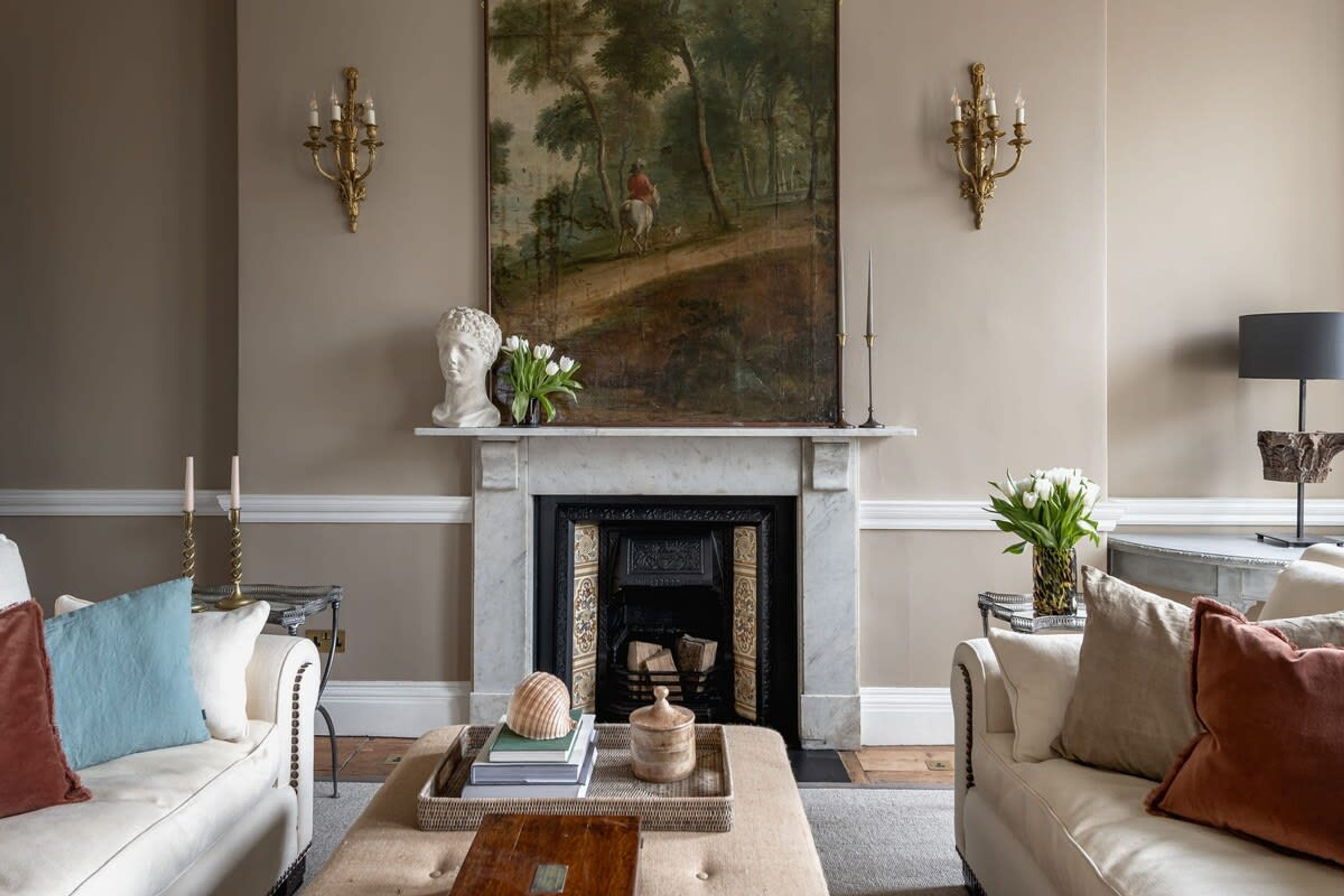 A living room with a fireplace, two sofas, a coffee table, and a painting on the wall.