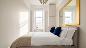 A bedroom with a bed, a large mirror, and a window. - Chic Sunlit Earls Court Flat (London)