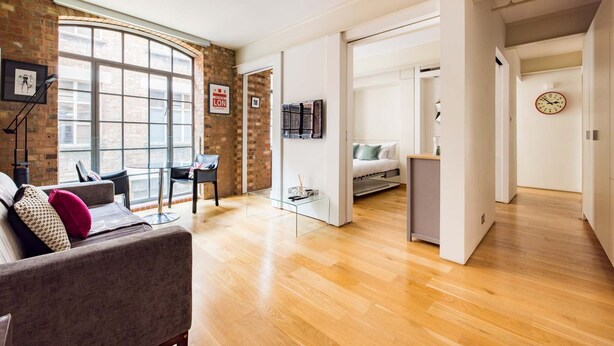 A modern living room with a large window, a sofa, a coffee table, and a TV. - Central Soho Loft With A C Concierge (London)