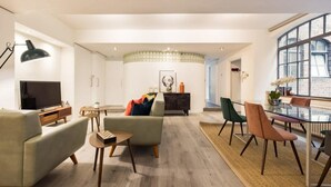 Un salon moderne comprenant un canapé, un téléviseur et un coin repas avec des chaises et une table.
