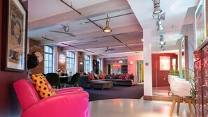 A spacious lounge area with a modern design, featuring a pink sofa, a black chair, and a wooden coffee table. - Luxurious Loft Central Soho - 3 Bedrooms Office (London)