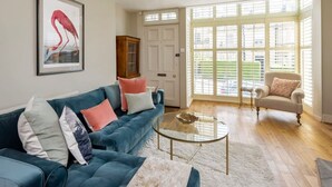 Ein Wohnzimmer mit einem blauen Sofa, einem Glastisch und einem Sessel.
