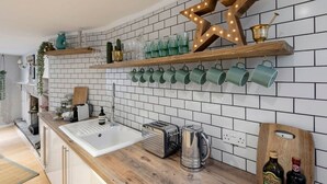 Eine moderne Küche mit weiß gefliestem Fliesenspiegel, Holzregalen und einer großen, beleuchteten Sterndekoration.
