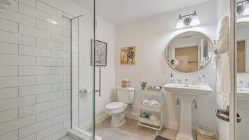 Une salle de bain moderne avec une douche à parois de verre, des toilettes, un lavabo avec un meuble-vasque et un grand miroir.