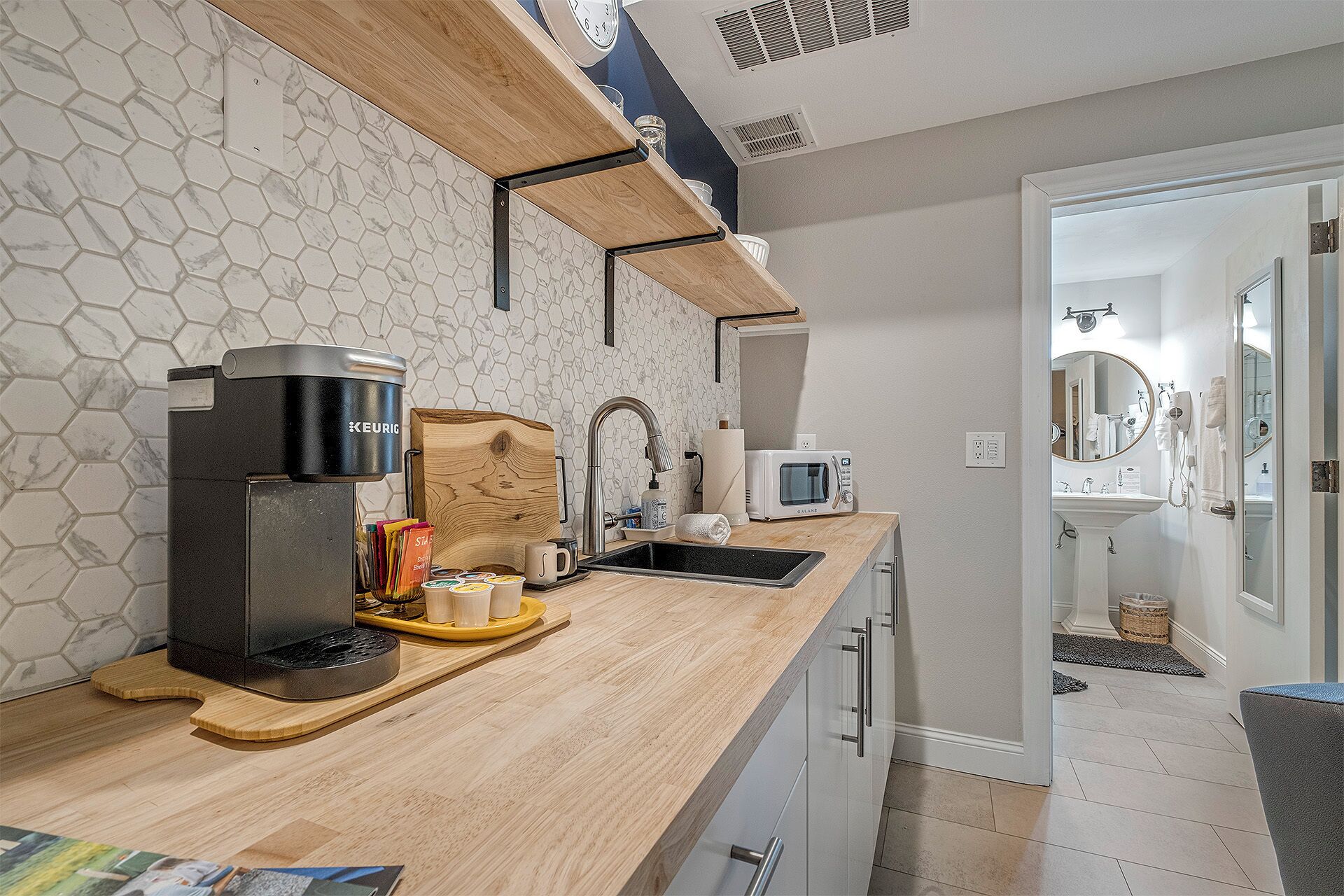 A modern kitchen with a coffee maker, microwave, and sink.