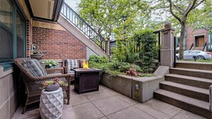 A patio with wicker furniture, a fire pit, and a planter with various plants. - The Orenco Station Hotel (Hillsboro)