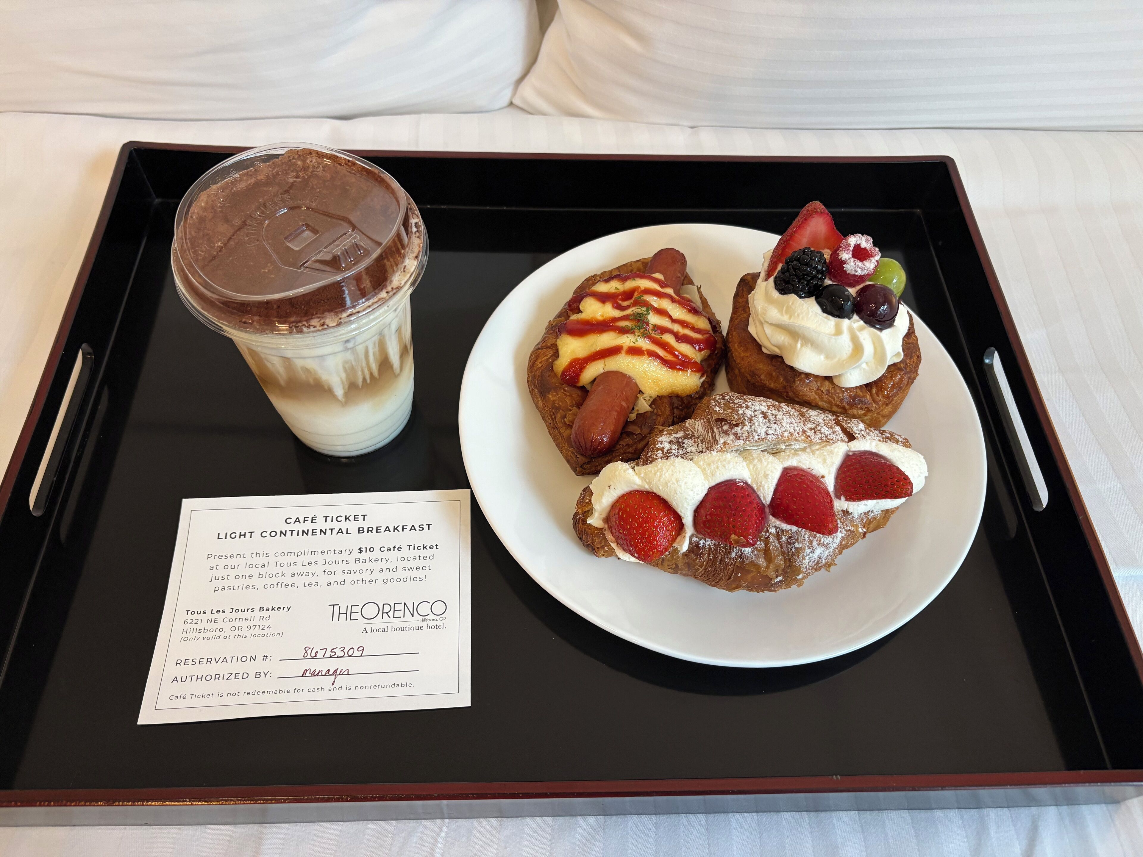 A tray with a dessert plate, a drink, and a café ticket.