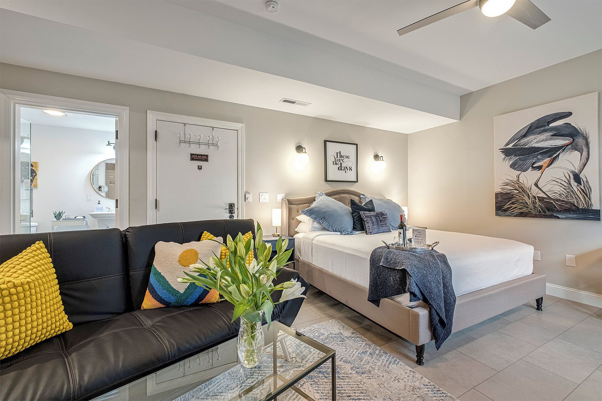 A modern bedroom with a bed, a sofa, a coffee table, and a painting.