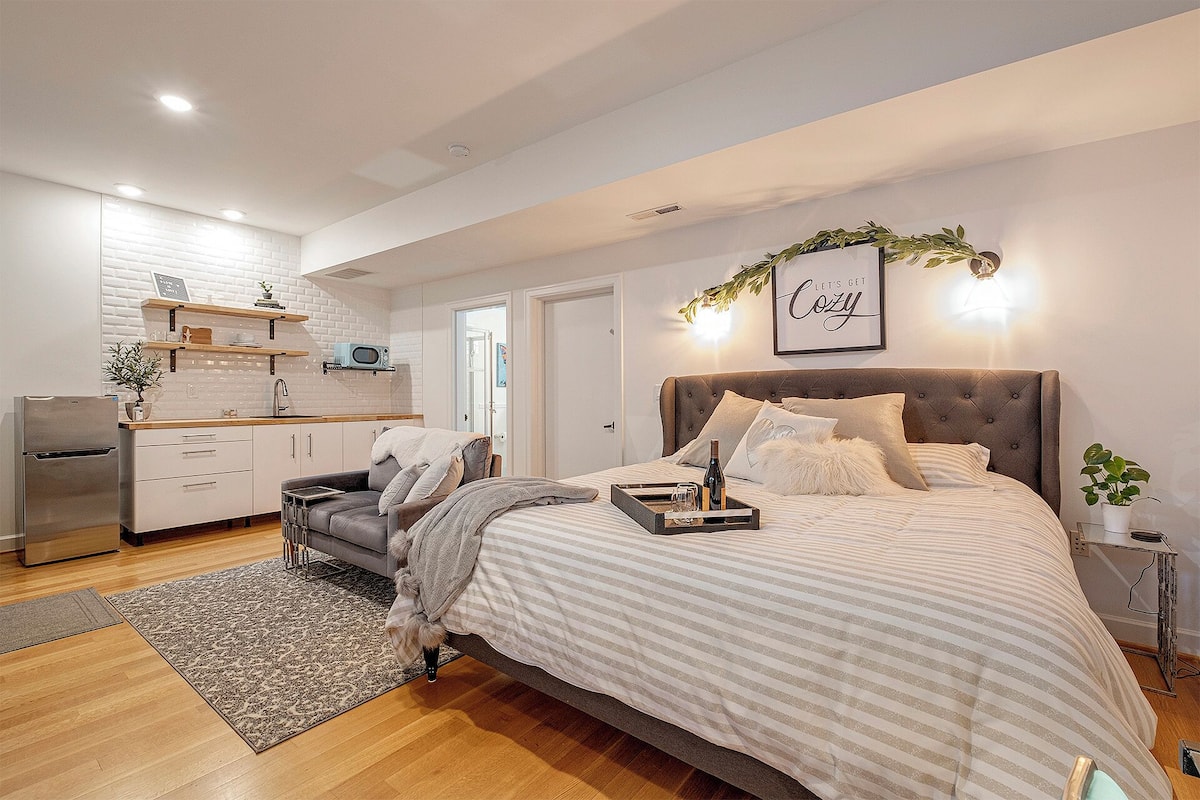 A modern bedroom with a large bed, a bedside table, a nightstand, and a wall-mounted TV.