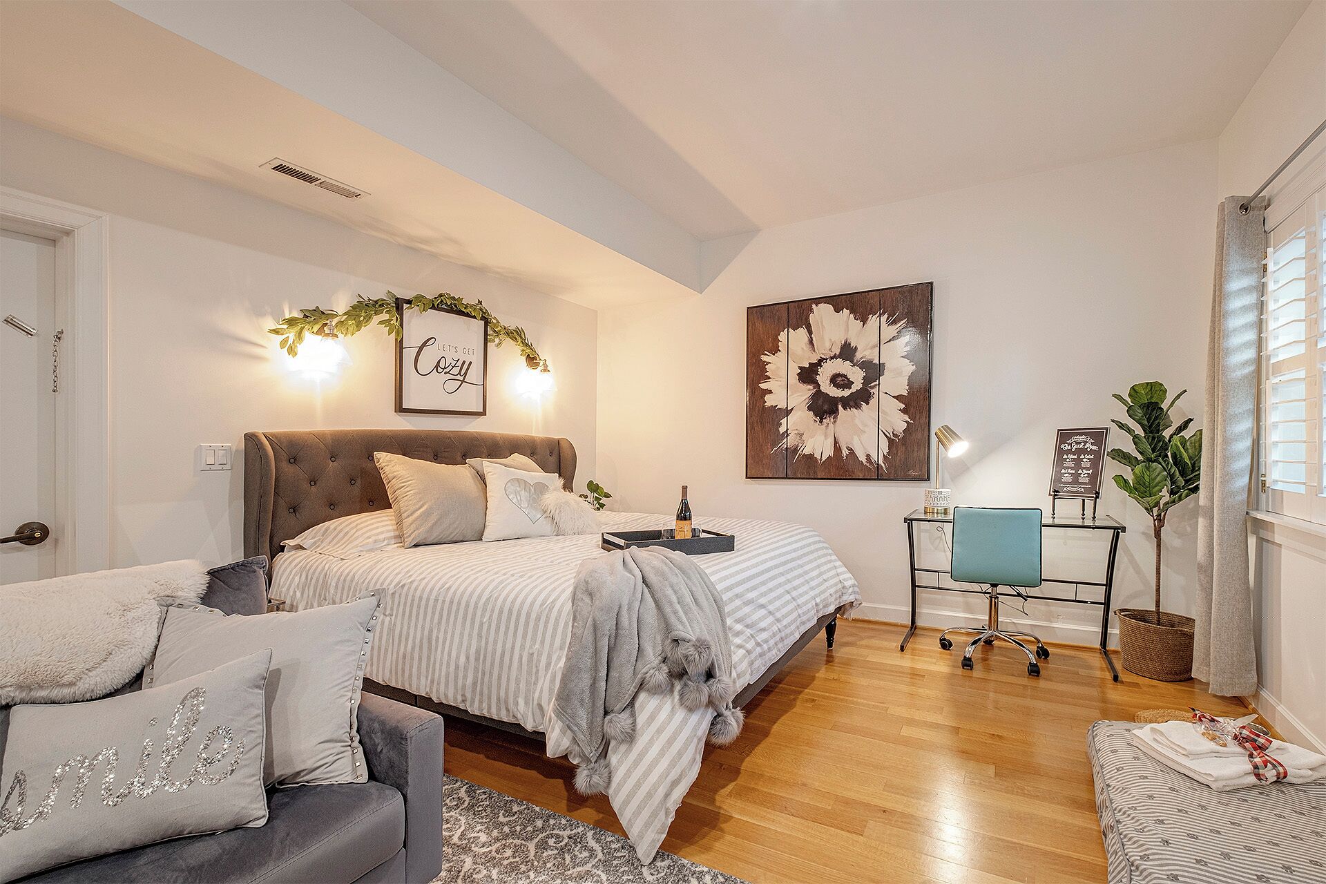 Un dormitorio con cama, mesita de noche, silla y escritorio con lámpara.