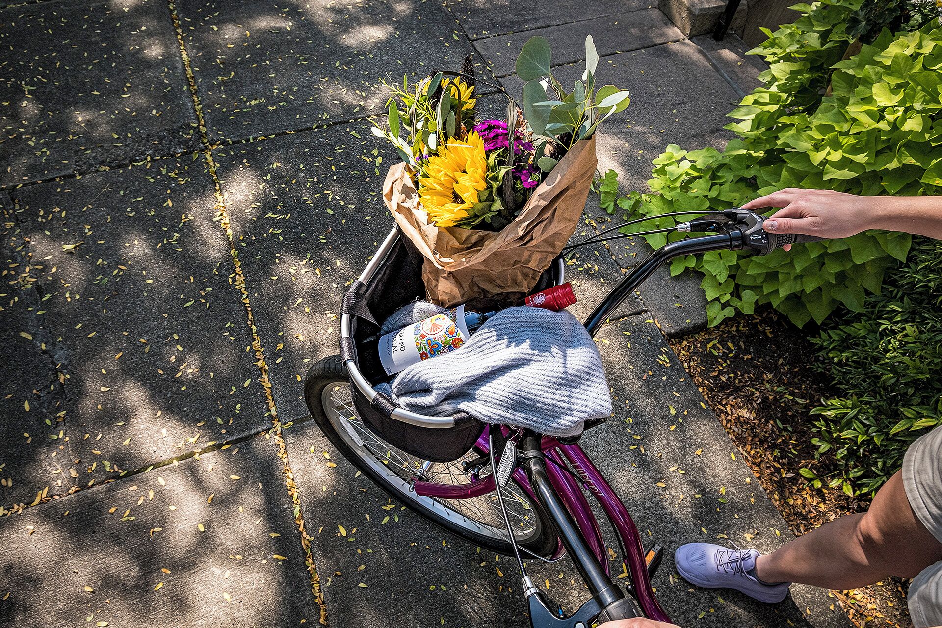 Una bicicleta con una cesta que contiene un ramo de flores y un objeto envuelto.
