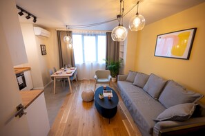 A modern living room with a sofa, a coffee table, and pendant lights. - Design 1bdr Apartment Near City Center (Sofia)