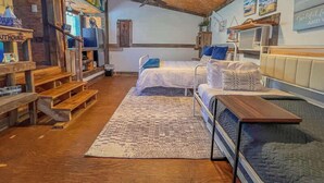 A cozy room with a wooden ceiling, a bed, a desk, and a bookshelf. - Surf Shack at Triple Z (Medicine Park)