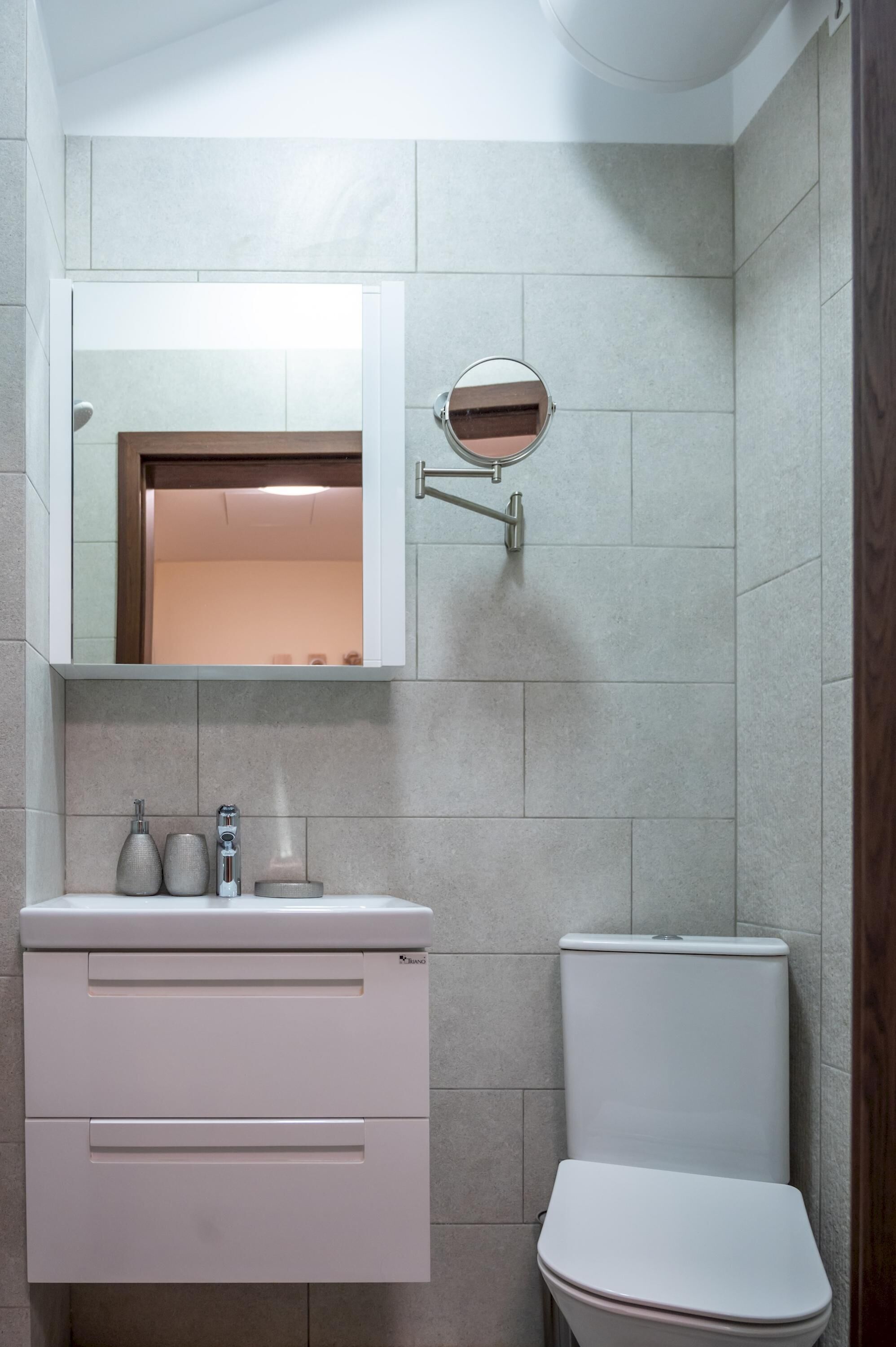 Ein Badezimmer mit einer weißen Toilette, einem Waschbecken mit Spiegel darüber und einem Handtuchhalter an der Wand.