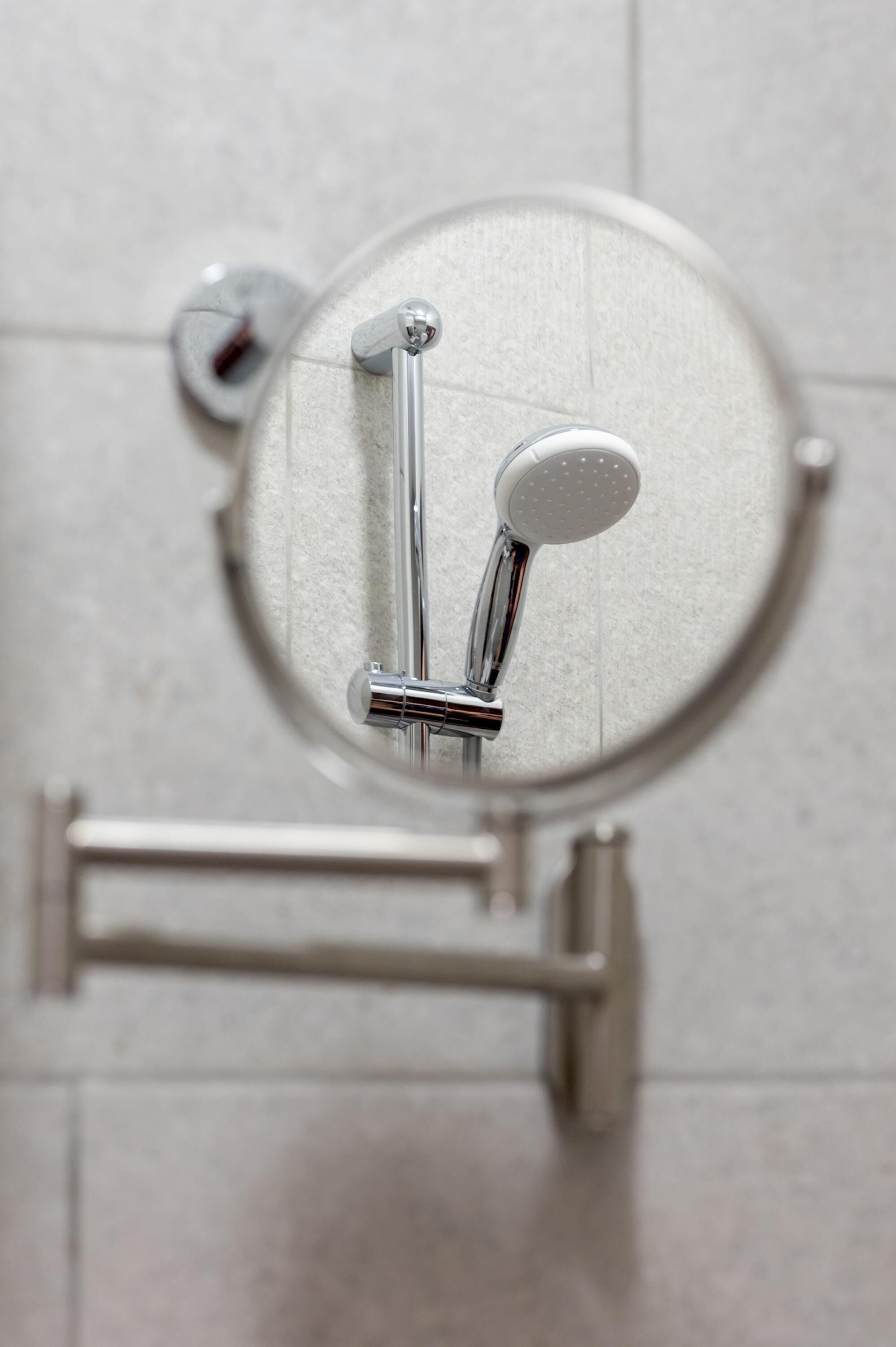 Ein modernes Badezimmer mit einer an der Wand montierten Duschbrause aus Chrom.