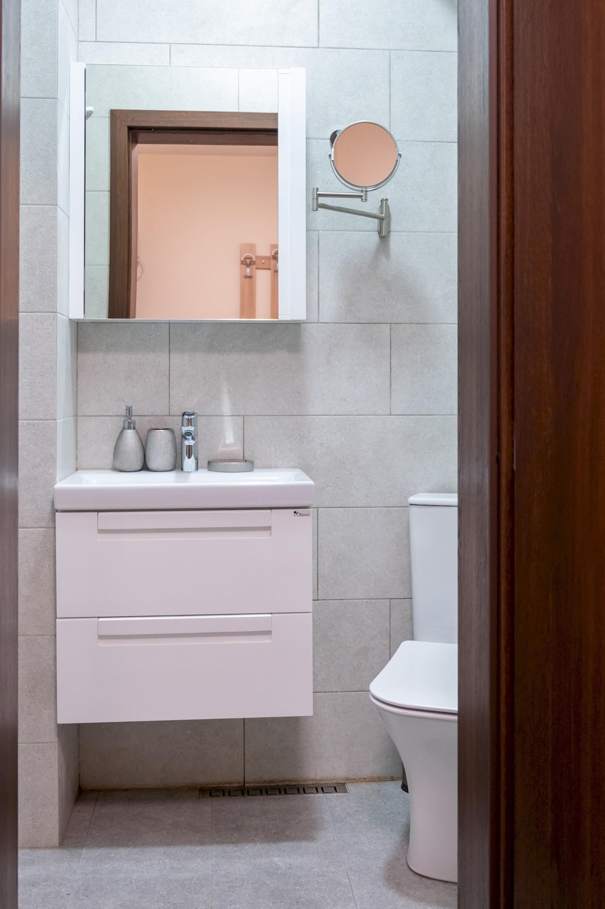 Un baño con un lavamanos blanco, un espejo y un inodoro.