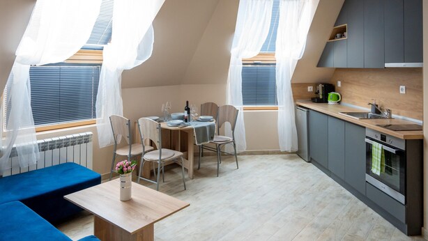 A compact kitchen with a dining area, a blue bench, and a small table with a vase of flowers. - Design Loft in the City Center (Sofia)