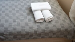 A neatly made bed with a patterned bedspread and two rolled towels on top. - Design Loft in the City Center (Sofia)