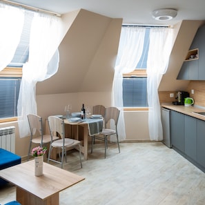 A modern kitchen with a dining area, featuring a table set for two, chairs, a coffee machine, and a small cabinet. - Design Loft in the City Center (Sofia)
