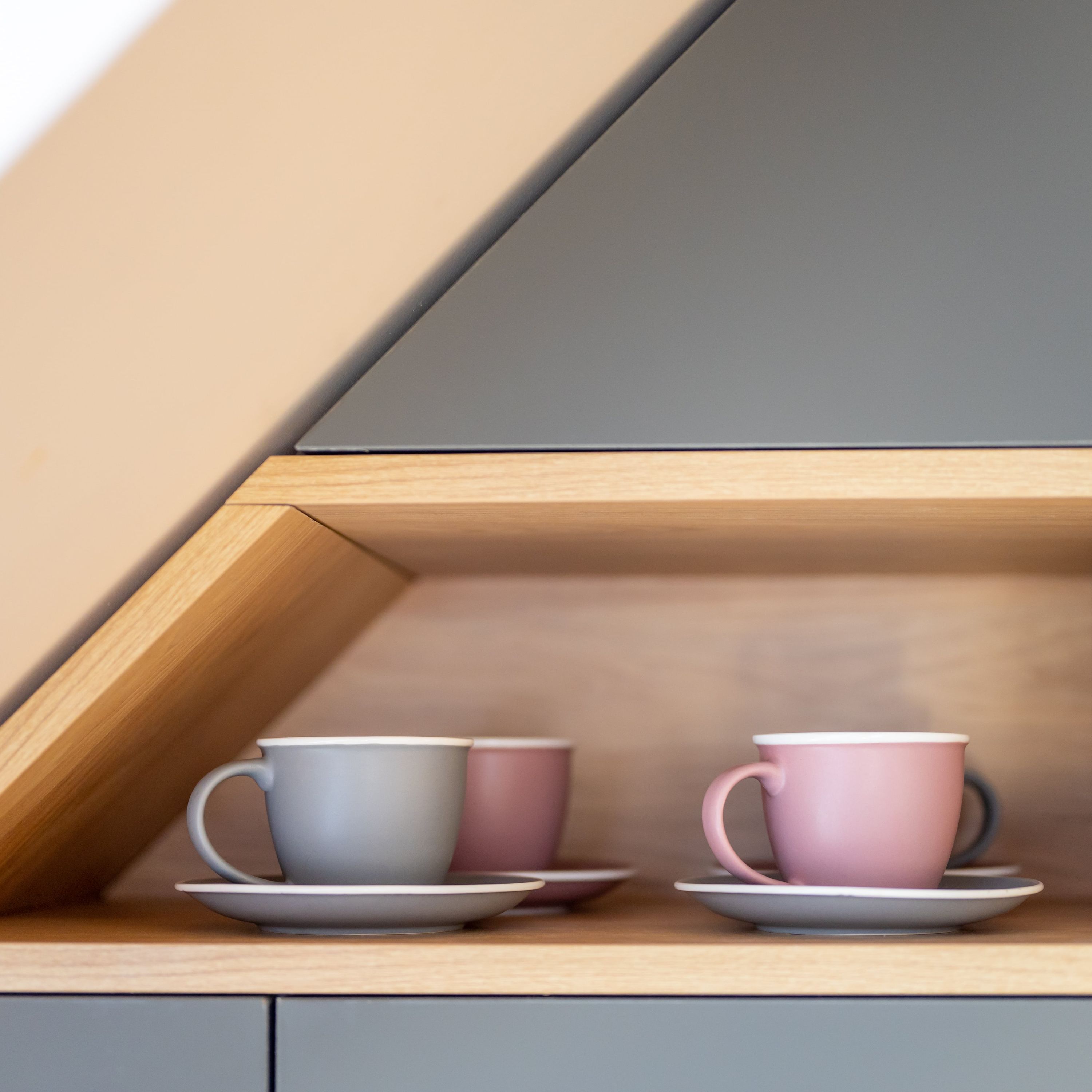 Une étagère en bois avec deux tasses et leurs soucoupes.