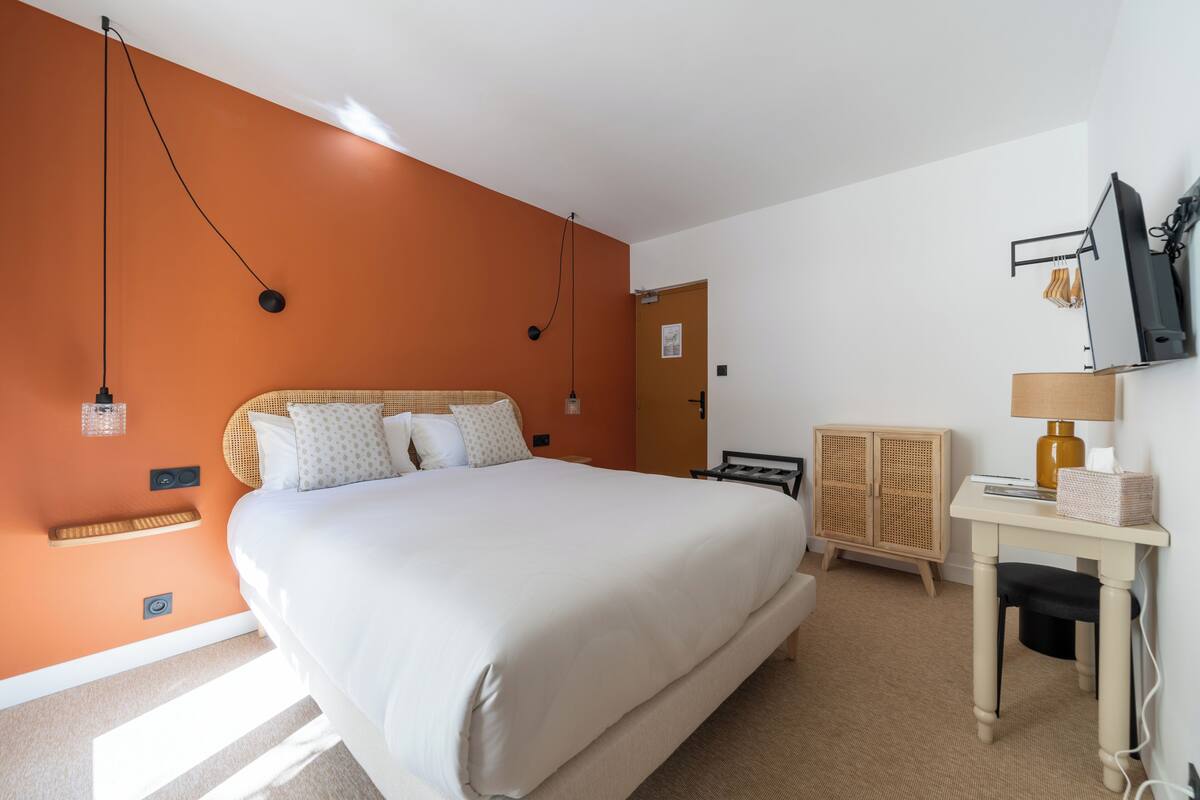 Una habitación de hotel con una cama grande, un escritorio, un armario y una televisión.