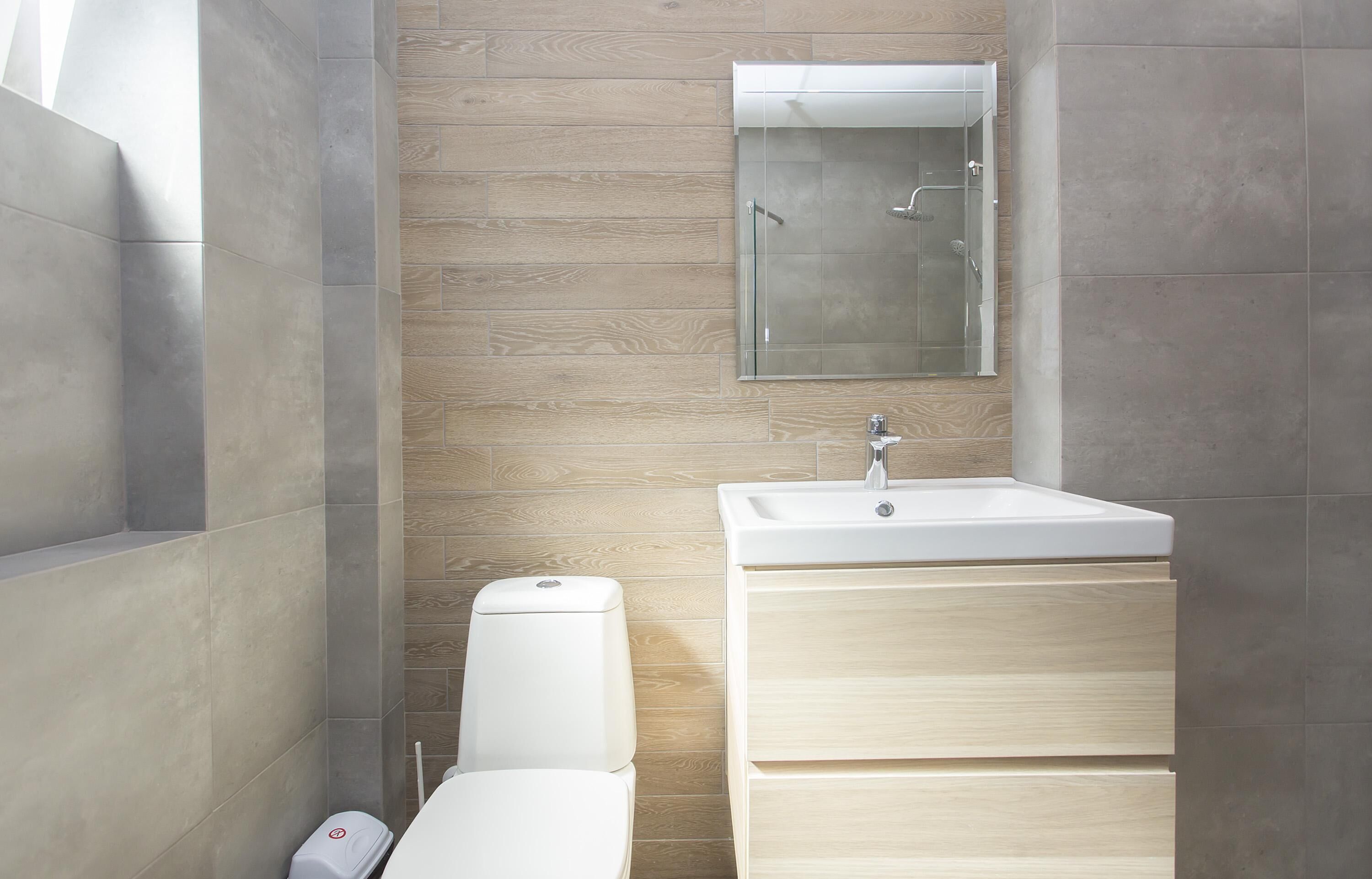 Un baño moderno con inodoro, lavamanos y cabina de ducha de vidrio.