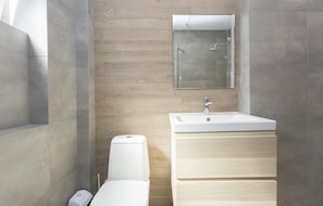 A modern bathroom with a toilet, sink, and glass shower enclosure. - Sunny and Modern 1bdr Apartment in the Center (Sofia)