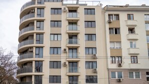 Een meerlaags woongebouw met balkons, airconditioning en verschillende soorten ramen.