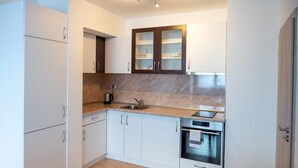 Een moderne keuken met witte kasten, een marmeren aanrecht, een ingebouwde oven en een koffiezetapparaat.