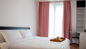 Een hotelkamer met een bed, een dienblad met ontbijtartikelen, een stoel en een wandplank.
