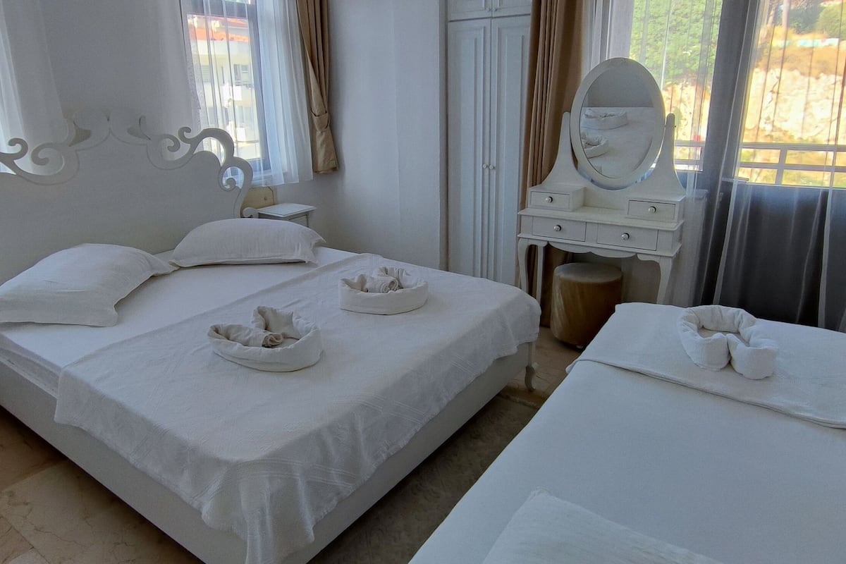 Une chambre d’hôtel avec deux lits, une coiffeuse avec un miroir et une petite table.