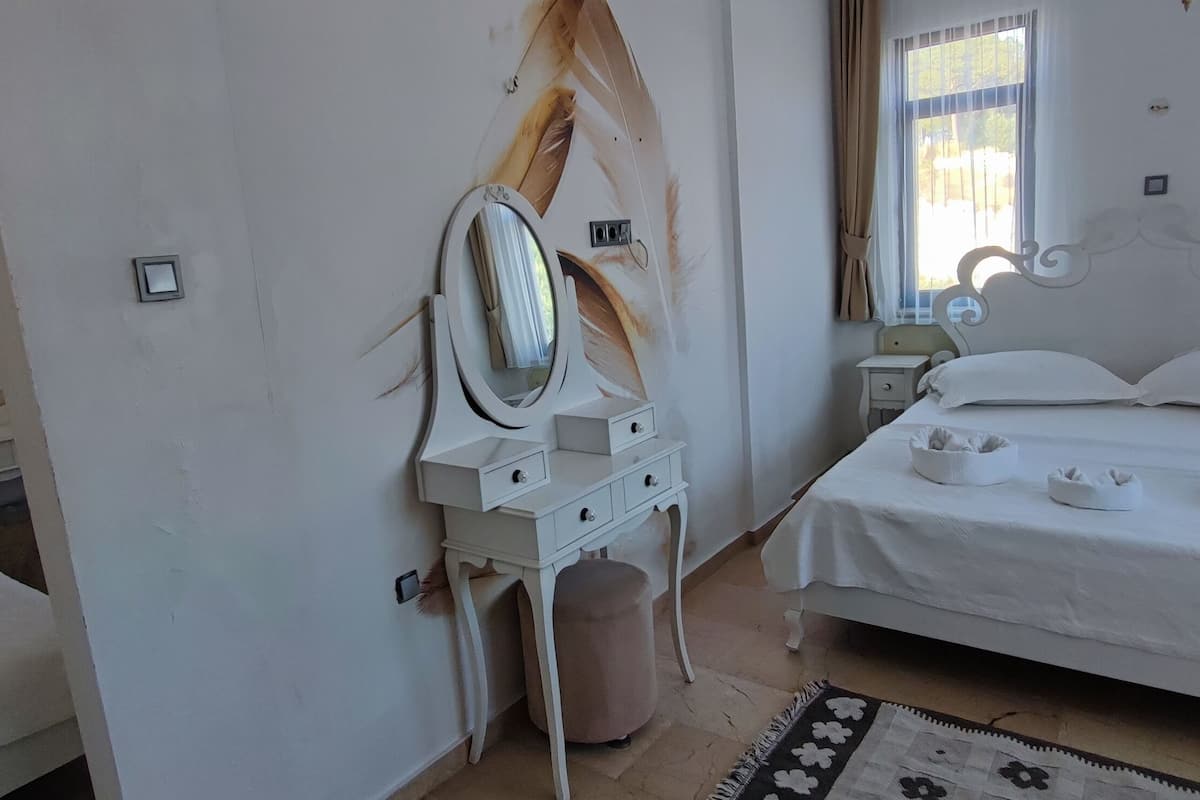 Une chambre à coucher avec un lit, une commode, un miroir et une fenêtre avec des rideaux.