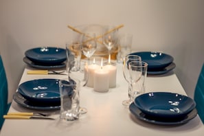 A table set with blue plates, clear glasses, and a lit candle.