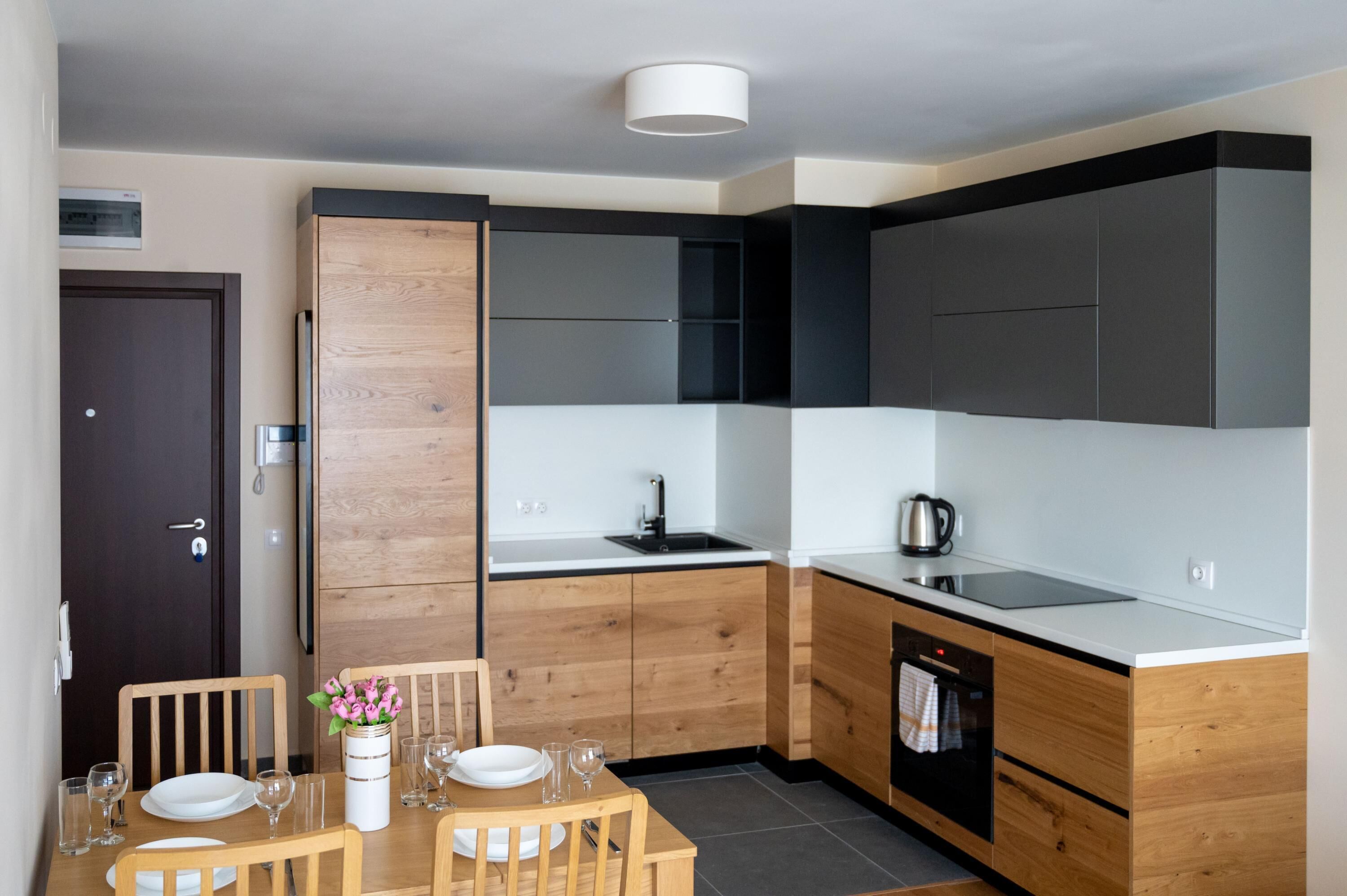 Una cocina moderna con armarios de madera, encimera negra y horno integrado.