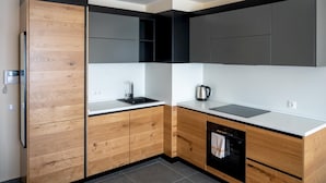 Una cucina moderna con mobili in legno, un piano di lavoro nero, un lavello e un bollitore.