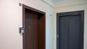 Una camera d'hotel con una porta in legno, un ascensore di colore scuro e un interruttore sulla parete.
