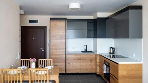 Una cucina moderna con pensili e basi in legno, forno integrato e zona pranzo con tavolo e sedie in legno.