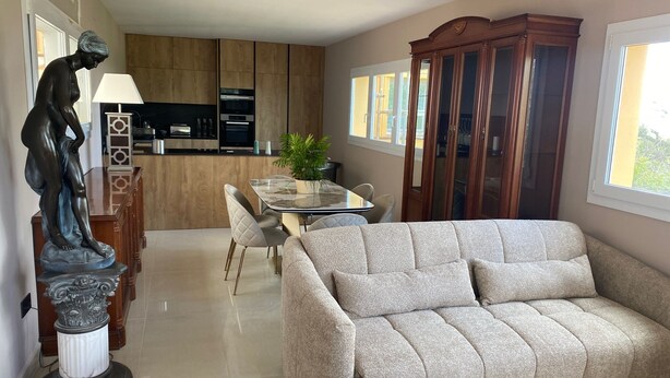 A modern living room with a beige sofa, a dining table with chairs, a statue, and a wooden cabinet. - Appatement Premium 2 Chambres (El Mas Isaac)