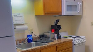 A kitchen with wooden cabinets, a white refrigerator, a microwave, a stove, and a sink.