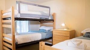 A bunk bed room with a desk and a lamp.