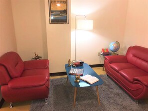 A room with two red leather armchairs, a blue coffee table with books, a globe, and a lamp. - 2 Bedroom Downtown Apt Friends Families Ideal (Pittsburgh)