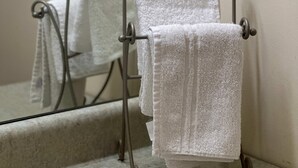 Un baño con un perchero metálico que sostiene dos toallas blancas.