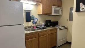 Una cocina con armarios de madera, un refrigerador blanco, un microondas, una estufa y un lavaplatos.