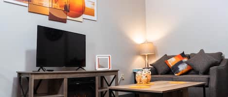 Una sala de estar con televisión de pantalla plana, chimenea, sofá y mesa de centro.