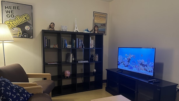 A living room with a TV, bookshelf, and a couch. - 2bedroom 2bathroom Apt Downtown Walk Anywhere (Pittsburgh)