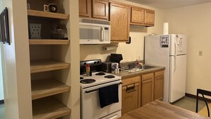 A kitchen with wooden cabinets, a white stove, a microwave, a refrigerator, and a dining table. - 2bedroom 2bathroom Apt Downtown Walk Anywhere (Pittsburgh)