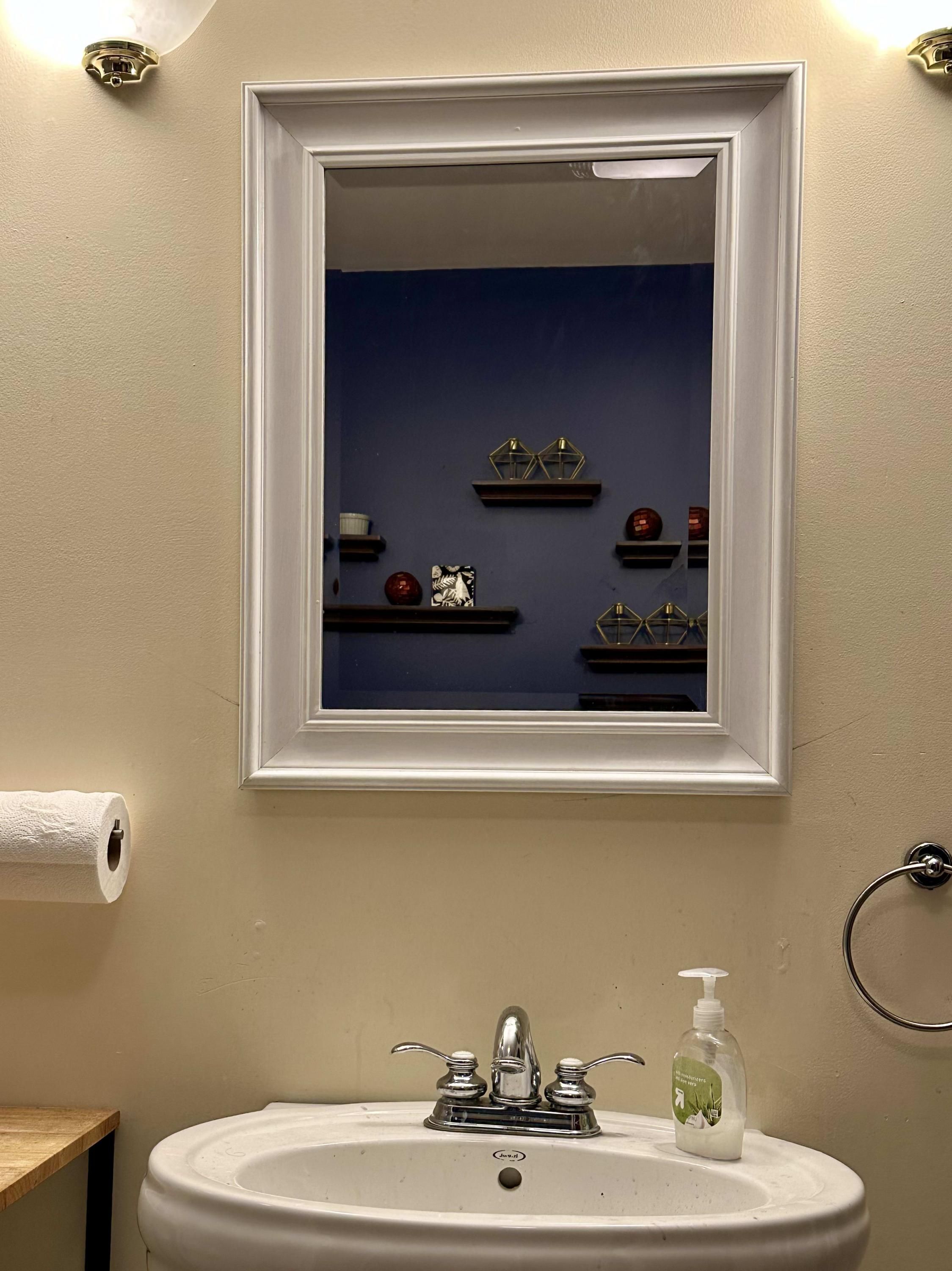 Un baño con un lavabo blanco, un espejo y un dispensador de papel higiénico.