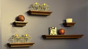 Una pared con cinco estantes, cada uno decorado con objetos ornamentales.