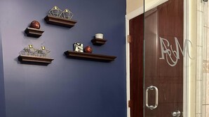 Un baño con inodoro, mampara de vidrio y pared azul decorada.